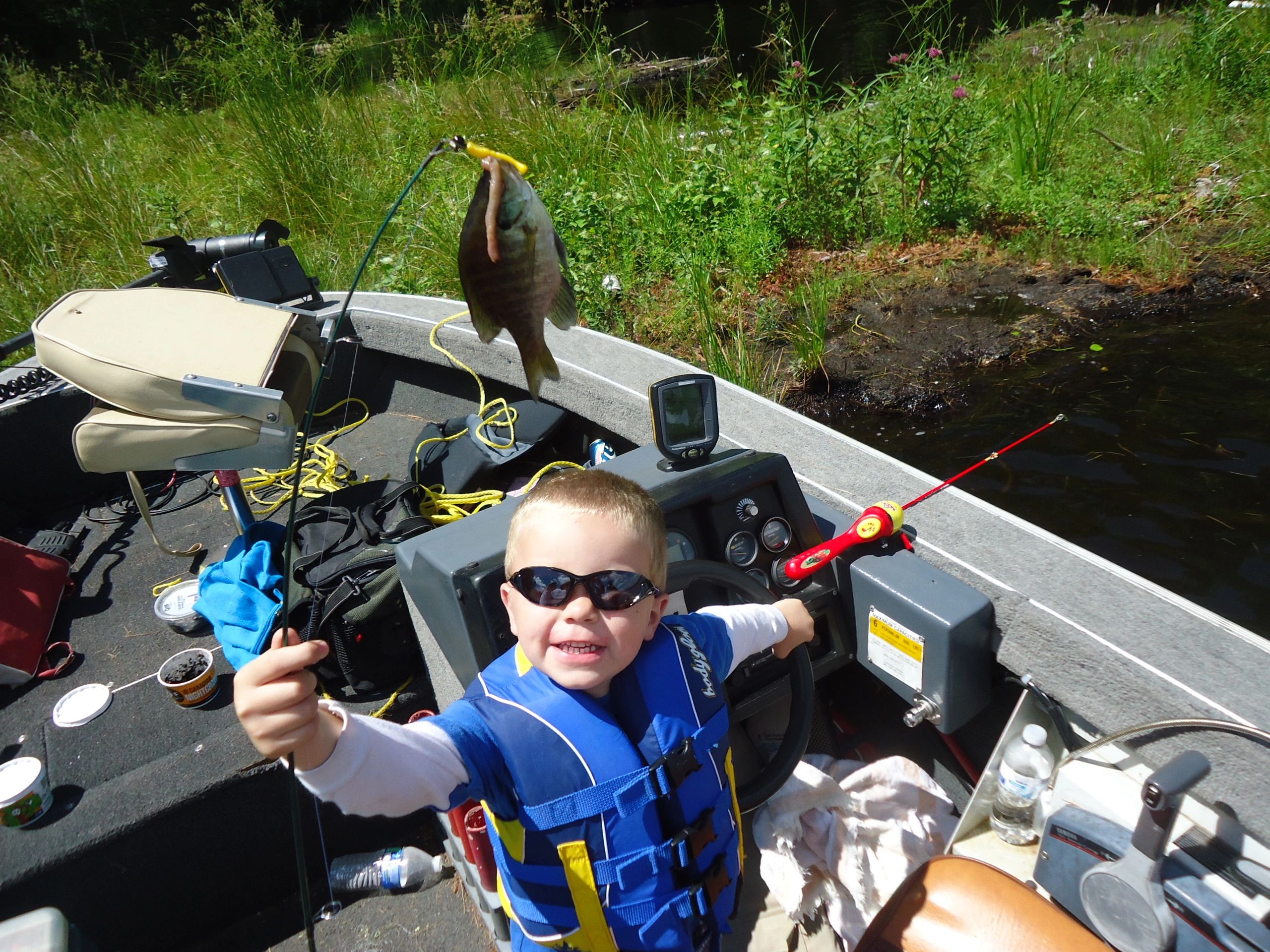 Child with sunglasses fishing in the boat
